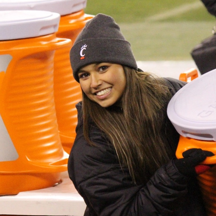 Bryn Cortez, 3rd year  in the Health Science - Pre Athletic Training Program, holds water on the football field. 