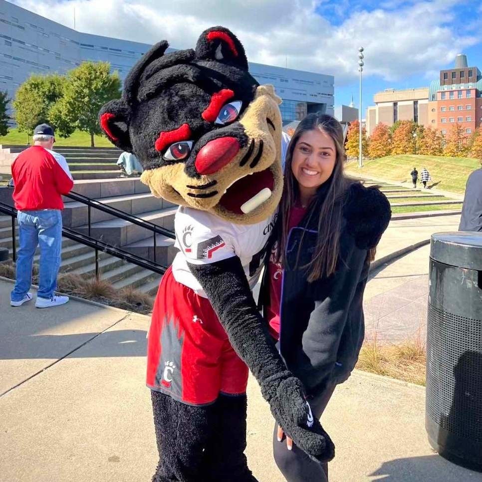 Esha Kothari, 4th year Health Sciences - Pre Occupational Therapy Program major, poses with UC's mascot.  