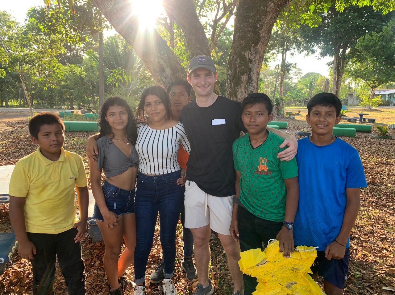 Student under a tree with children from Costa Rica. 